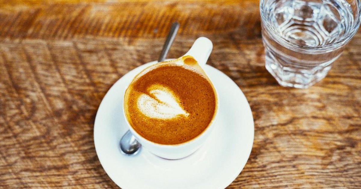 A cup of coffee and a glass of water on a wooden table
