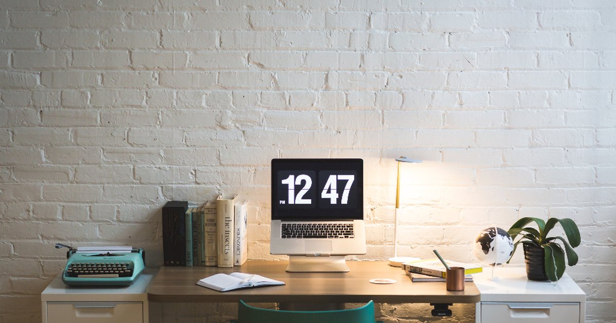 A home office desk with a laptop screen showing 12:47 PM