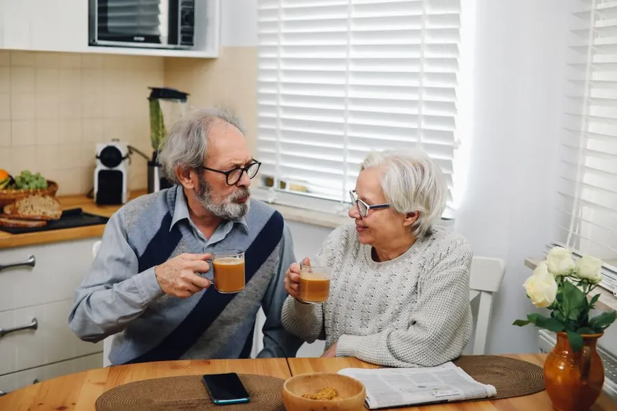 Older couple having coffee together in a kitchen, the everyday context of tracking a supplement at home