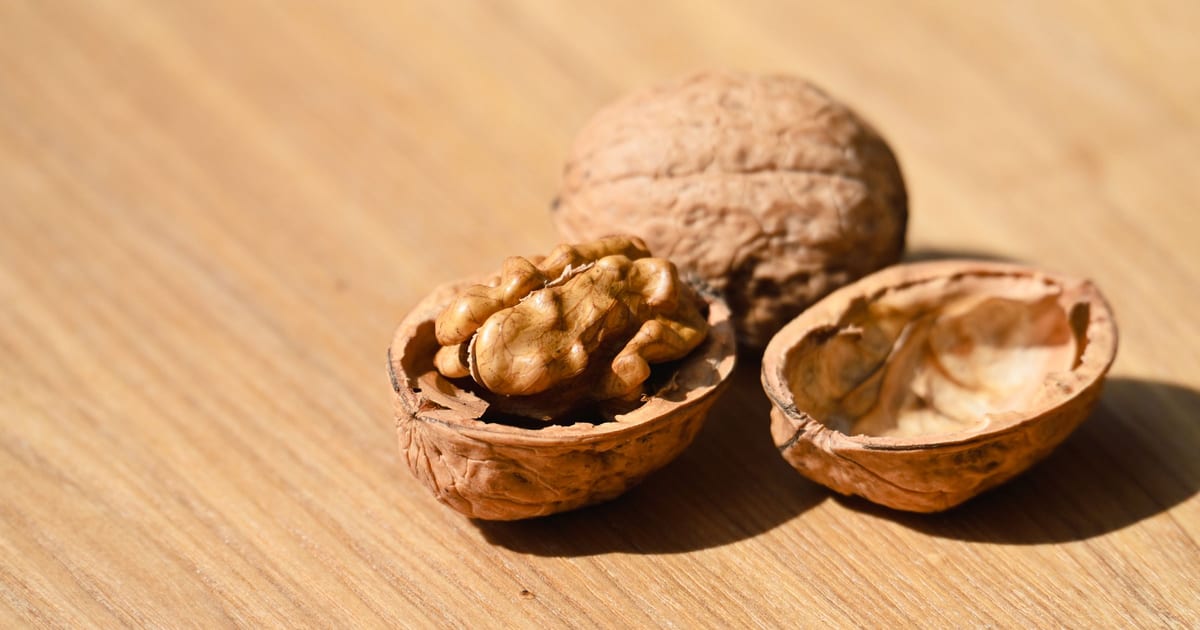 Walnuts on a wooden table, one whole and one cracked open