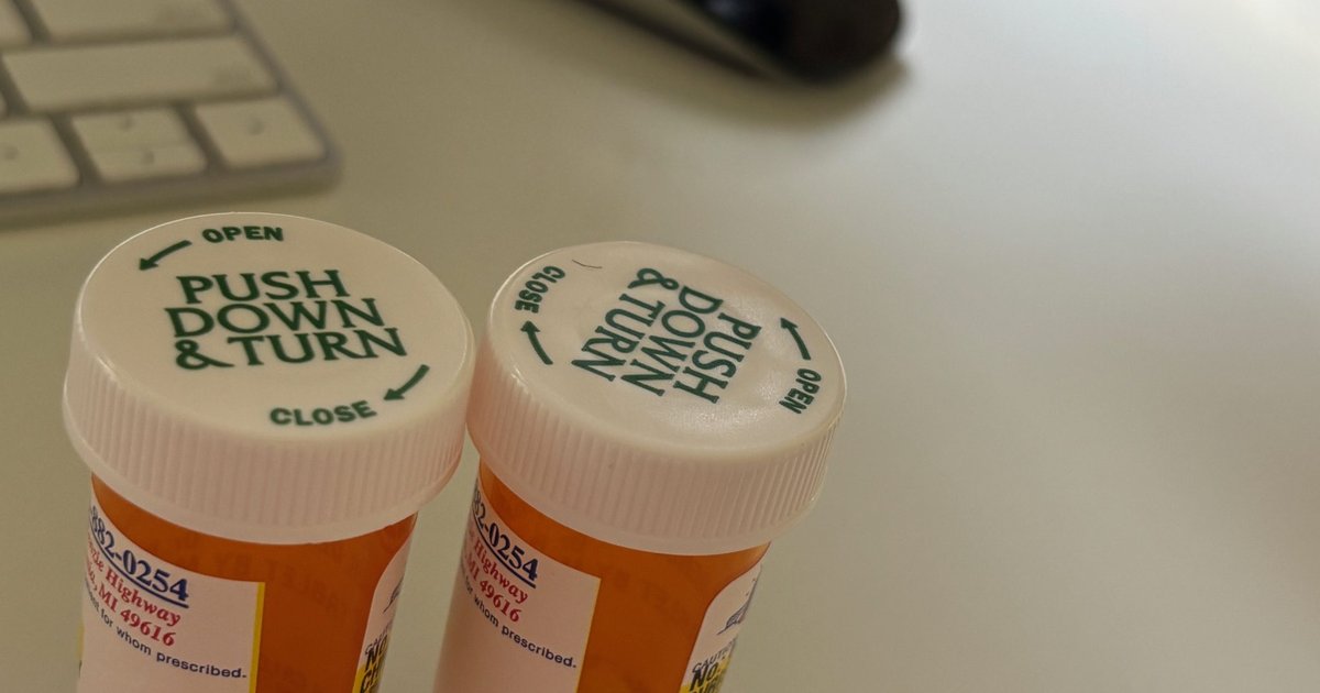 Two prescription pill bottles with childproof caps on a desk