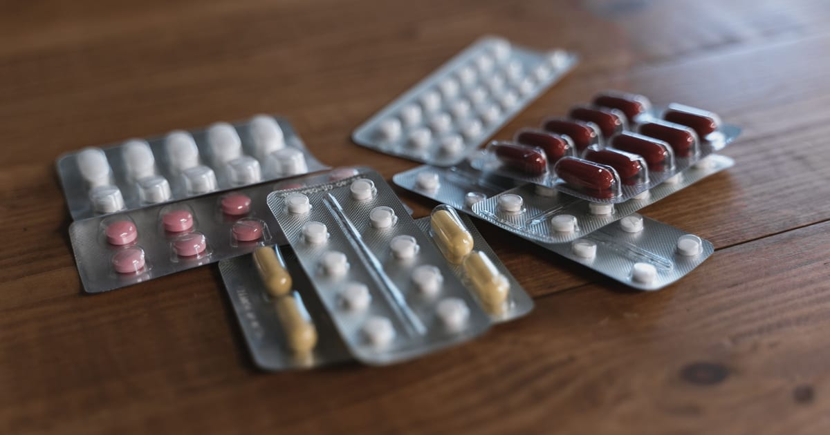 Several blister packs of tablets and capsules on a wooden table