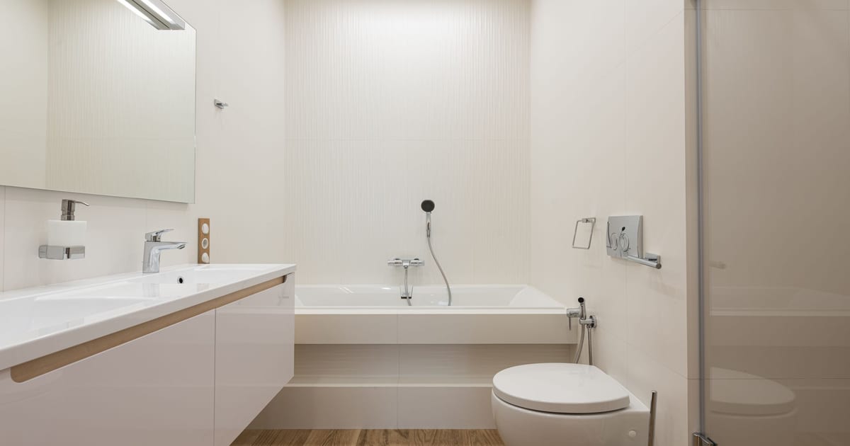 A bright, modern bathroom with a wall-hung toilet, a bathtub and a long white vanity